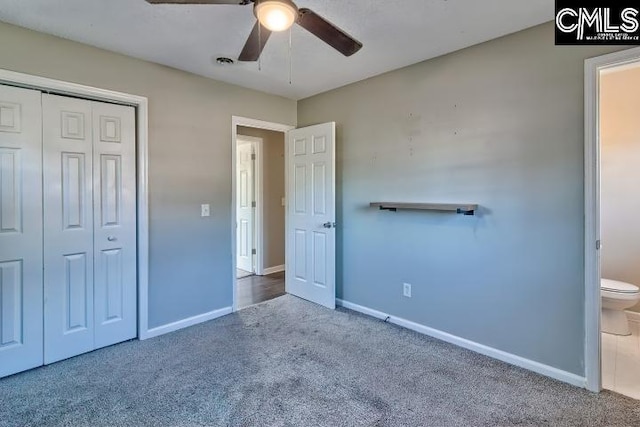 unfurnished bedroom with ceiling fan, a closet, ensuite bathroom, and carpet flooring