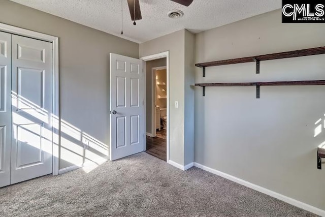 unfurnished bedroom with ceiling fan, light colored carpet, a textured ceiling, and a closet