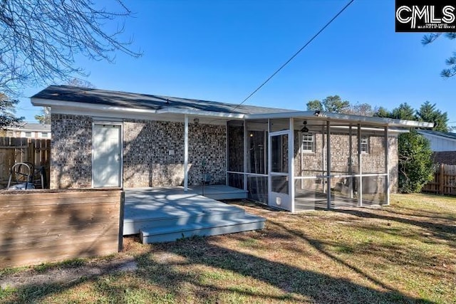 rear view of property with a lawn and a sunroom