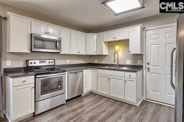 kitchen featuring sink, hardwood / wood-style flooring, stainless steel appliances, and white cabinetry