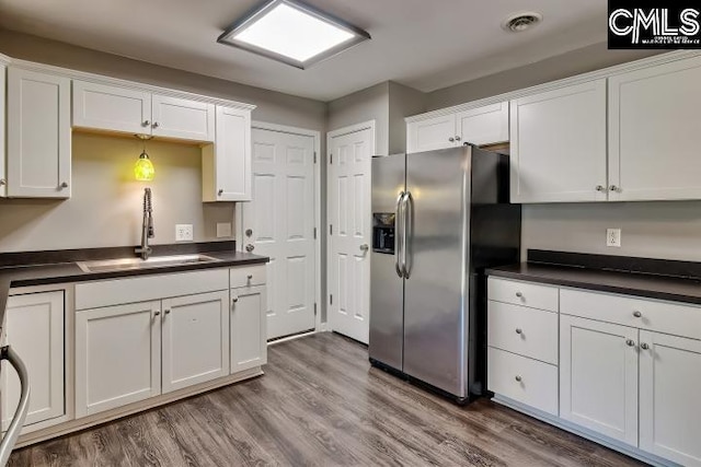 kitchen featuring wood-type flooring, sink, white cabinetry, and stainless steel fridge with ice dispenser