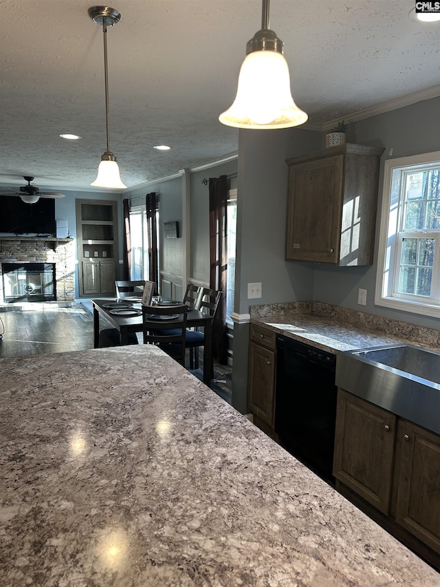 kitchen featuring plenty of natural light, a textured ceiling, black dishwasher, and a fireplace