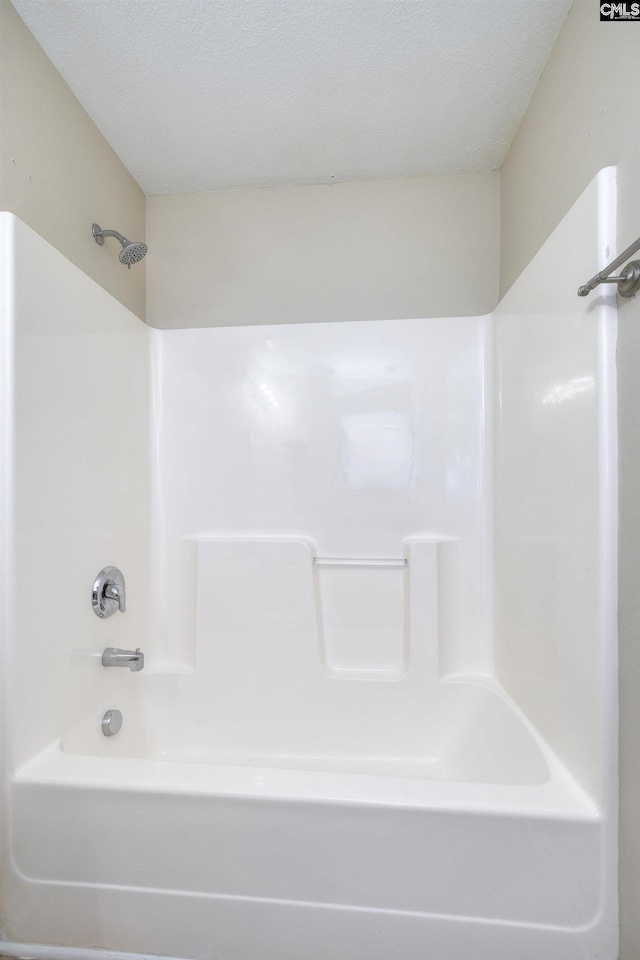 bathroom with a textured ceiling and shower / washtub combination