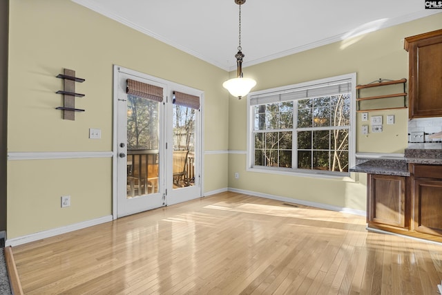 unfurnished dining area featuring crown molding and light wood-type flooring