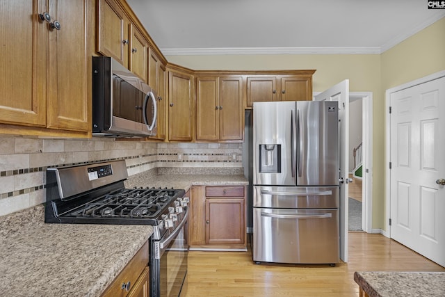 kitchen with appliances with stainless steel finishes, ornamental molding, light hardwood / wood-style flooring, and backsplash