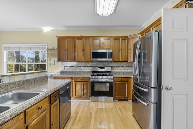 kitchen featuring backsplash, sink, crown molding, light wood-type flooring, and stainless steel appliances