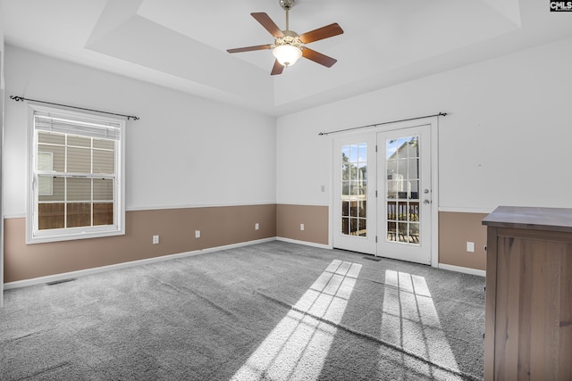 carpeted empty room with a raised ceiling and ceiling fan