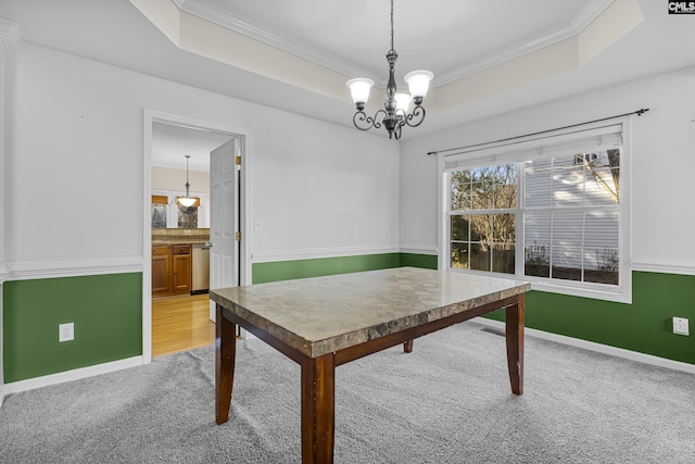 unfurnished dining area with crown molding, light colored carpet, an inviting chandelier, and a tray ceiling