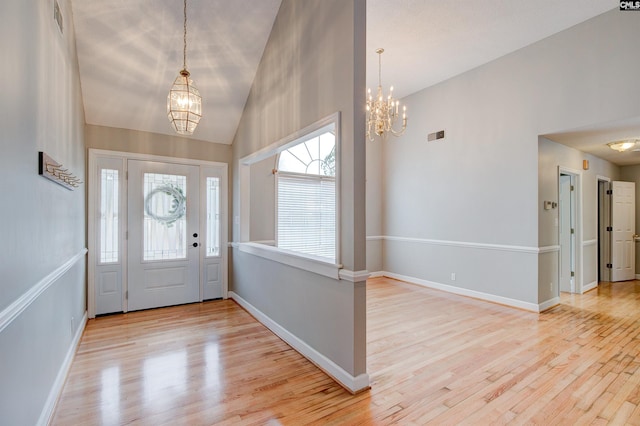 foyer featuring high vaulted ceiling, light hardwood / wood-style floors, and a chandelier