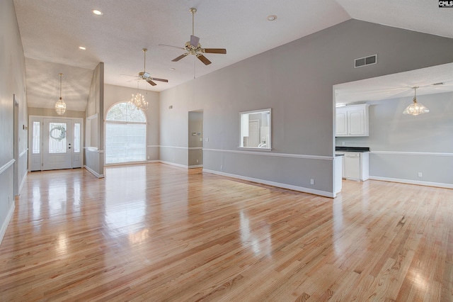 unfurnished living room with high vaulted ceiling, light wood-style flooring, and visible vents