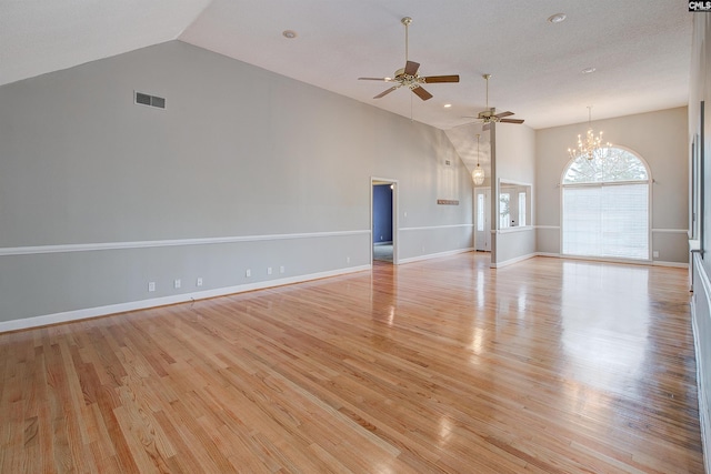 unfurnished living room with high vaulted ceiling, ceiling fan with notable chandelier, and light hardwood / wood-style floors