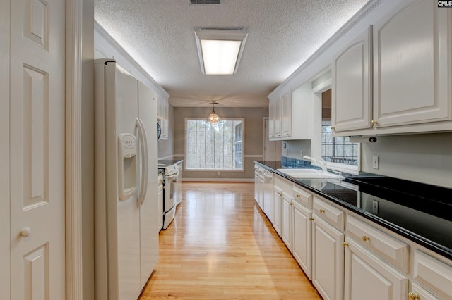 kitchen with decorative light fixtures, sink, white appliances, white cabinetry, and a textured ceiling