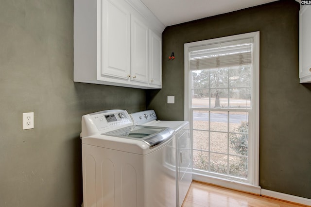 laundry area with light wood-type flooring, cabinet space, and independent washer and dryer