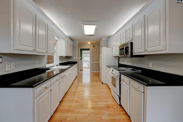 kitchen with white cabinetry, white appliances, light wood-type flooring, a textured ceiling, and sink