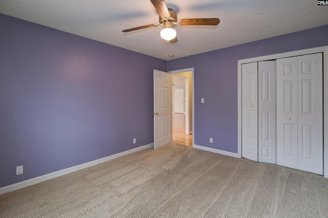 unfurnished bedroom with ceiling fan, a textured ceiling, a closet, and carpet flooring