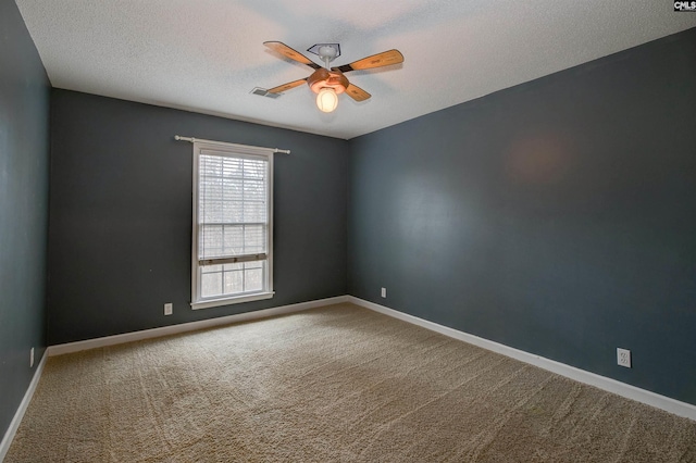 carpeted spare room featuring a ceiling fan, visible vents, a textured ceiling, and baseboards