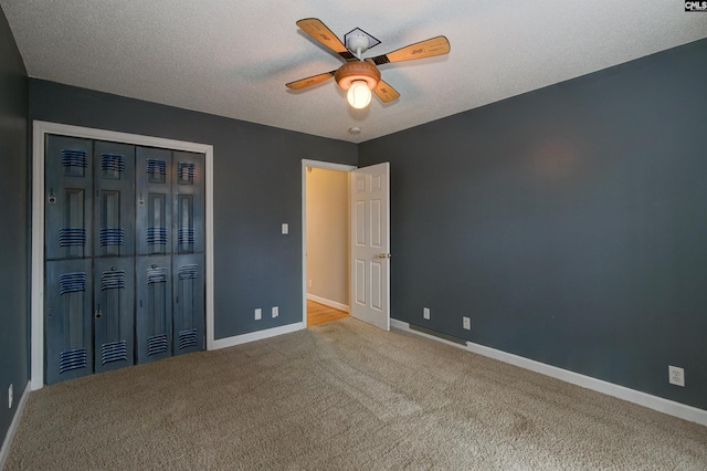 unfurnished bedroom with carpet, a closet, a ceiling fan, a textured ceiling, and baseboards