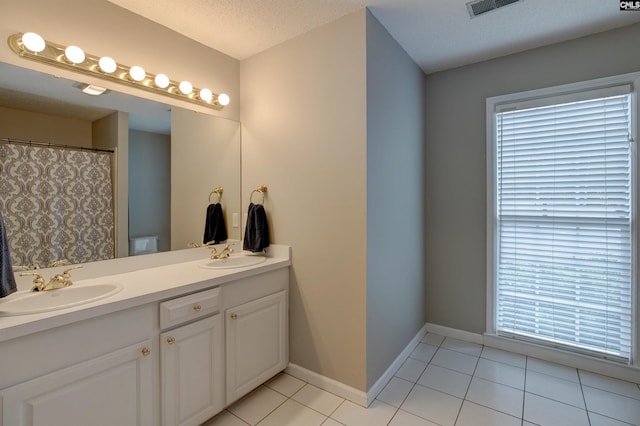 bathroom featuring toilet, vanity, tile patterned flooring, and a textured ceiling