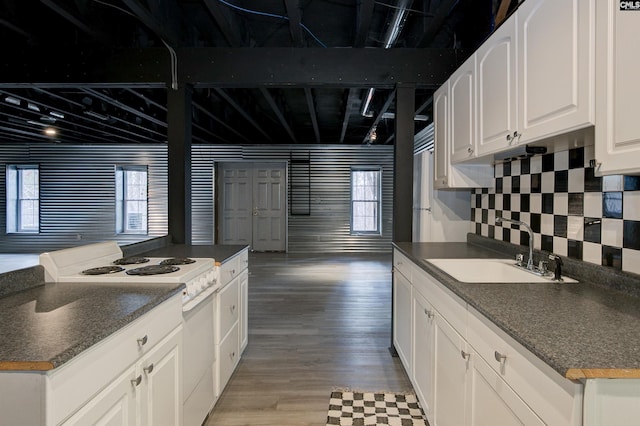 kitchen with white range with electric cooktop, a sink, light wood finished floors, beamed ceiling, and dark countertops