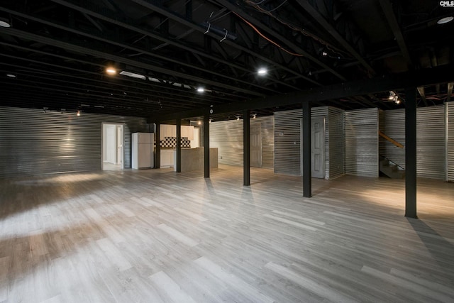 basement featuring hardwood / wood-style flooring and white refrigerator