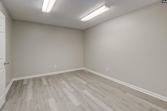 spare room featuring a textured ceiling and light hardwood / wood-style floors