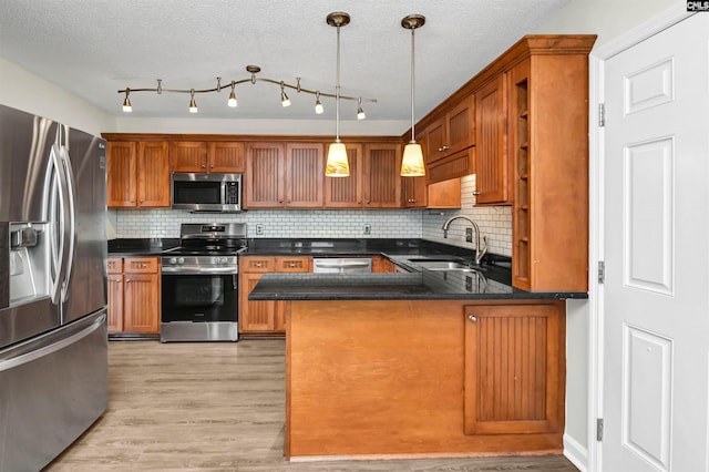 kitchen with light hardwood / wood-style floors, stainless steel appliances, decorative backsplash, decorative light fixtures, and sink