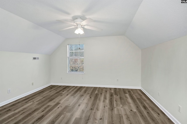 additional living space featuring a textured ceiling, ceiling fan, dark hardwood / wood-style flooring, and lofted ceiling