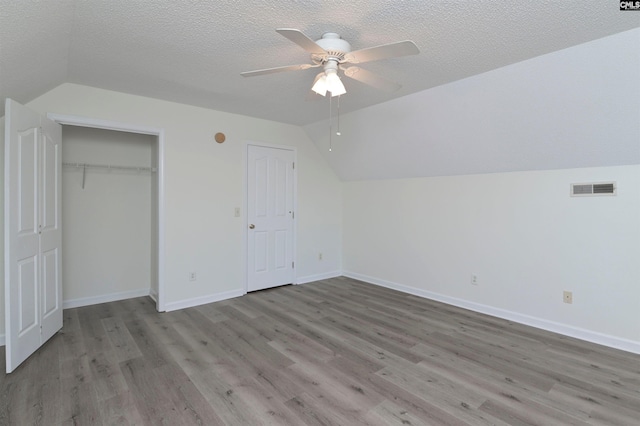 unfurnished bedroom with ceiling fan, vaulted ceiling, a textured ceiling, and light hardwood / wood-style flooring