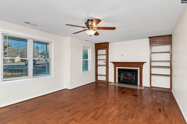 unfurnished living room featuring ceiling fan, a textured ceiling, and dark hardwood / wood-style flooring