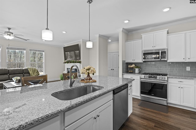 kitchen featuring dark wood-style floors, hanging light fixtures, decorative backsplash, appliances with stainless steel finishes, and a sink