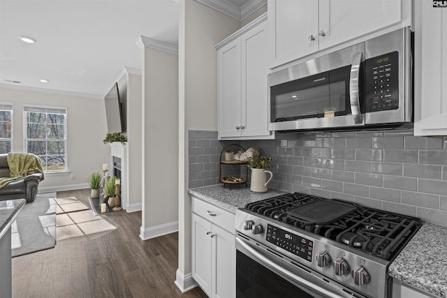 kitchen featuring dark wood-style floors, stainless steel appliances, open floor plan, and crown molding