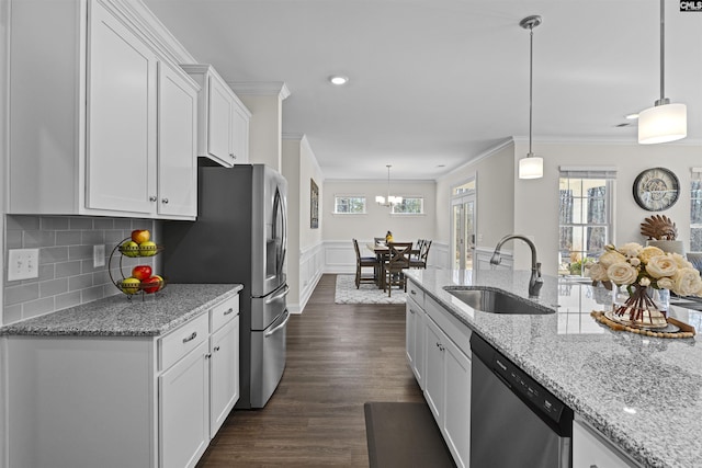 kitchen featuring crown molding, appliances with stainless steel finishes, white cabinets, a sink, and wainscoting