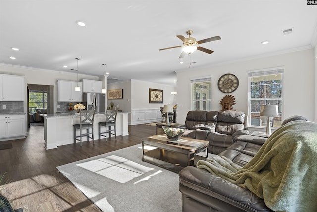 living area featuring ceiling fan, recessed lighting, visible vents, dark wood finished floors, and crown molding