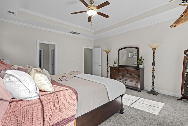 carpeted bedroom featuring baseboards, visible vents, a raised ceiling, and ornamental molding