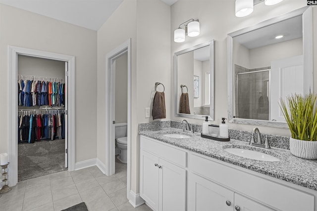 bathroom featuring toilet, a stall shower, a sink, and tile patterned floors