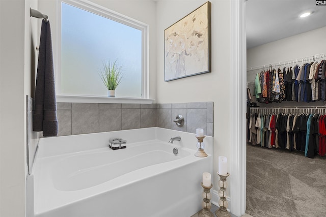 full bathroom with a spacious closet and a bath