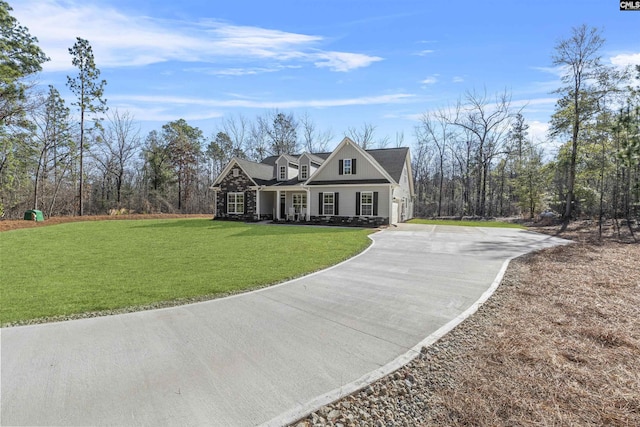 view of front of house with stone siding, a front yard, and concrete driveway