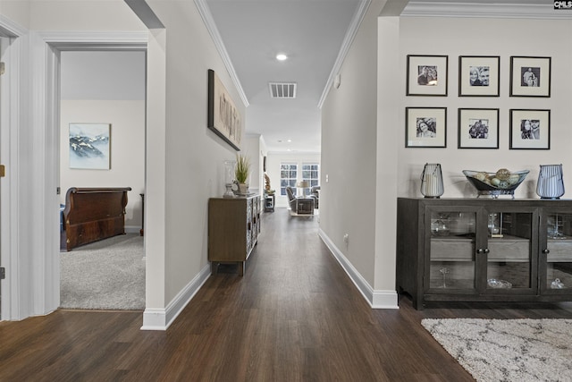 corridor with ornamental molding, wood finished floors, visible vents, and baseboards