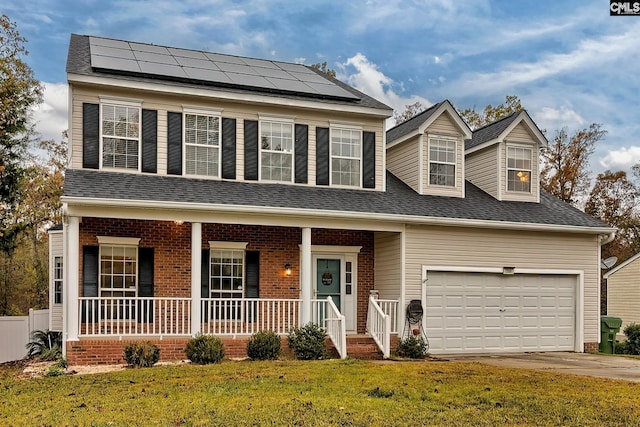 view of front facade featuring a front yard, covered porch, a garage, and solar panels