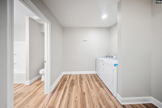 laundry area with light hardwood / wood-style floors and washer and clothes dryer