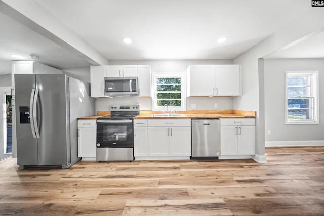 kitchen featuring appliances with stainless steel finishes, butcher block counters, and white cabinets