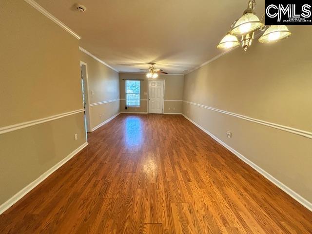 empty room featuring ceiling fan, crown molding, baseboards, and wood finished floors