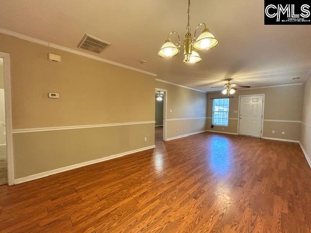 spare room featuring baseboards, crown molding, visible vents, and wood finished floors