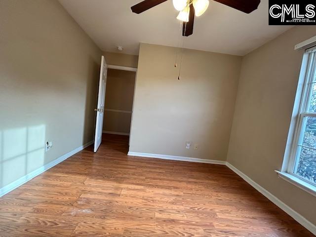 empty room featuring a ceiling fan, baseboards, and wood finished floors