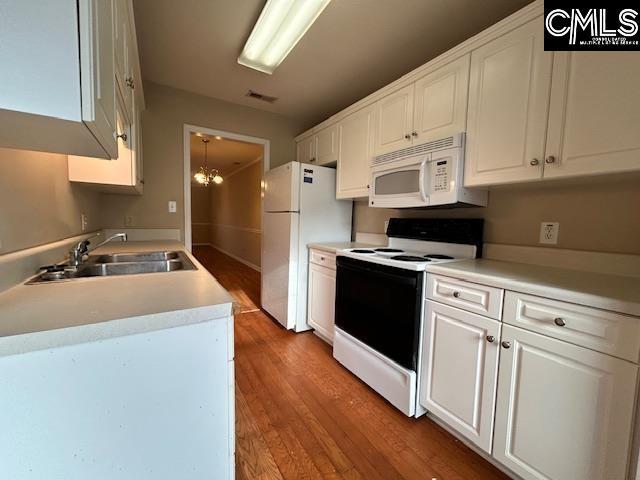 kitchen featuring sink, hardwood / wood-style flooring, white cabinetry, white appliances, and a notable chandelier