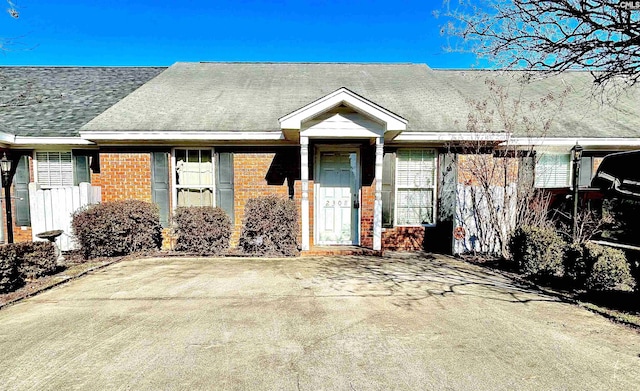 view of front of house with a shingled roof and brick siding