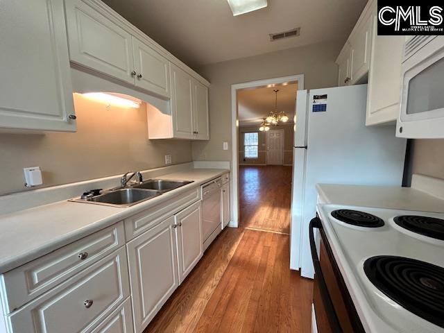 kitchen with white appliances, white cabinets, sink, a chandelier, and light wood-type flooring