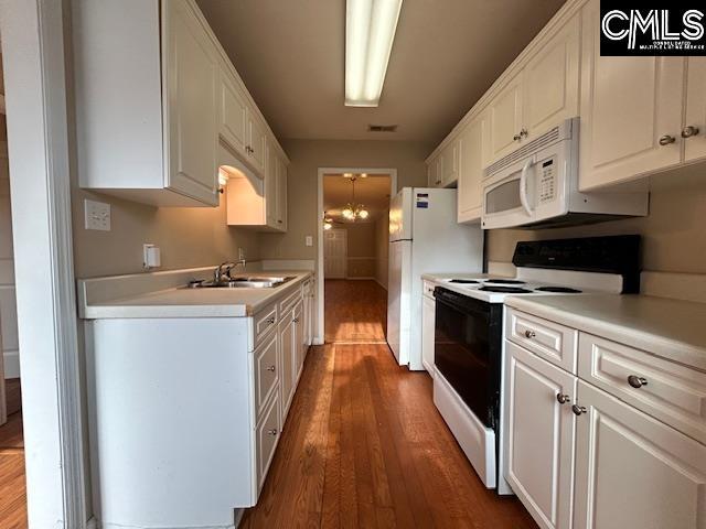 kitchen featuring light countertops, white appliances, a sink, and white cabinetry