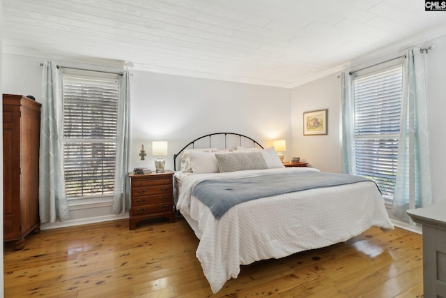 bedroom featuring light hardwood / wood-style floors, wooden ceiling, and ornamental molding