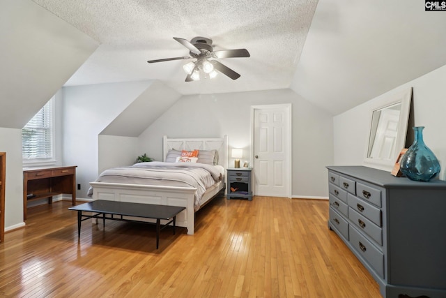 bedroom with a textured ceiling, ceiling fan, lofted ceiling, and light hardwood / wood-style floors